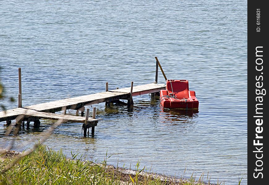 Small beautiful wooden pier jetty with a floating armchair. Small beautiful wooden pier jetty with a floating armchair