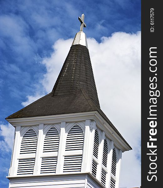 Conceptual view of church steeple against blue sky and white clouds