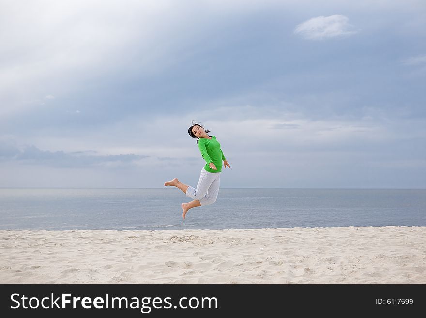 Attractive brunette woman jumping on the beach. Attractive brunette woman jumping on the beach