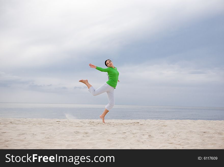 Attractive brunette woman jumping on the beach. Attractive brunette woman jumping on the beach