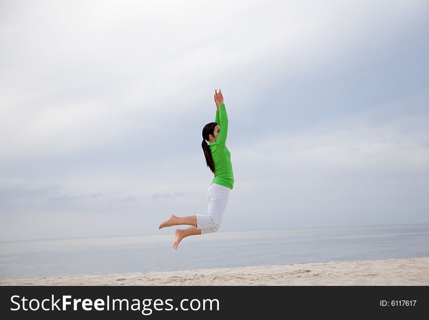 Attractive brunette woman jumping on the beach. Attractive brunette woman jumping on the beach