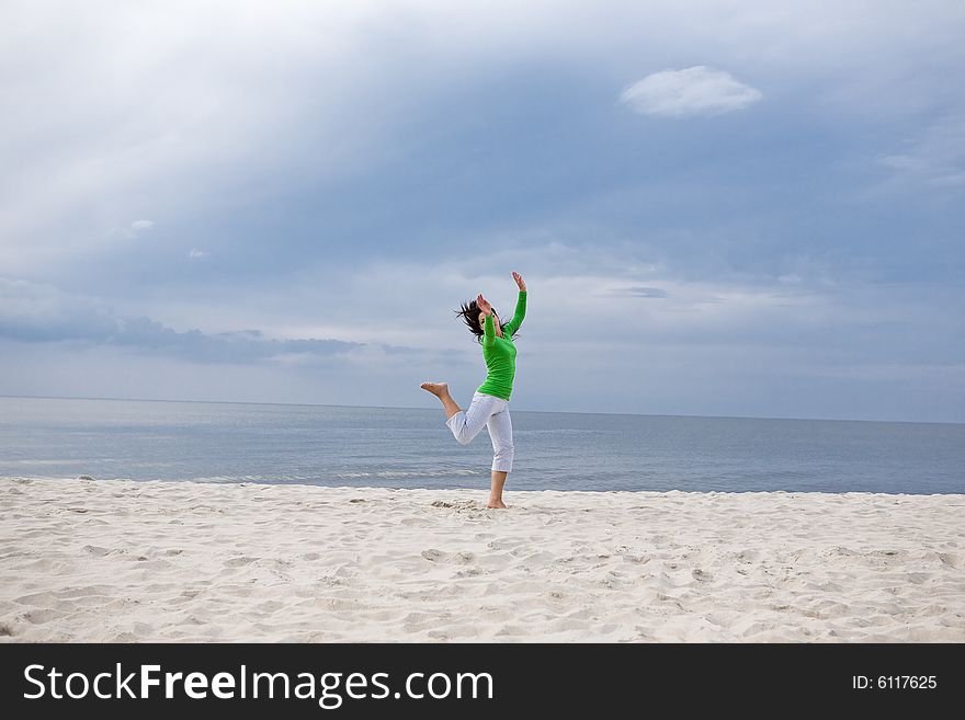 Attractive brunette woman jumping on the beach. Attractive brunette woman jumping on the beach