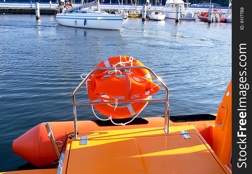Details of the orange life-saving equipment on board rescue motor boat. Yachts in background.