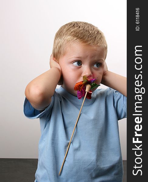 Toddler playing with a wind toy, holding his ears. Toddler playing with a wind toy, holding his ears