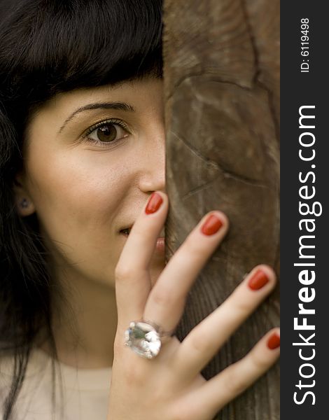 Closeup portrait of young attractive girl hiding behind a tree