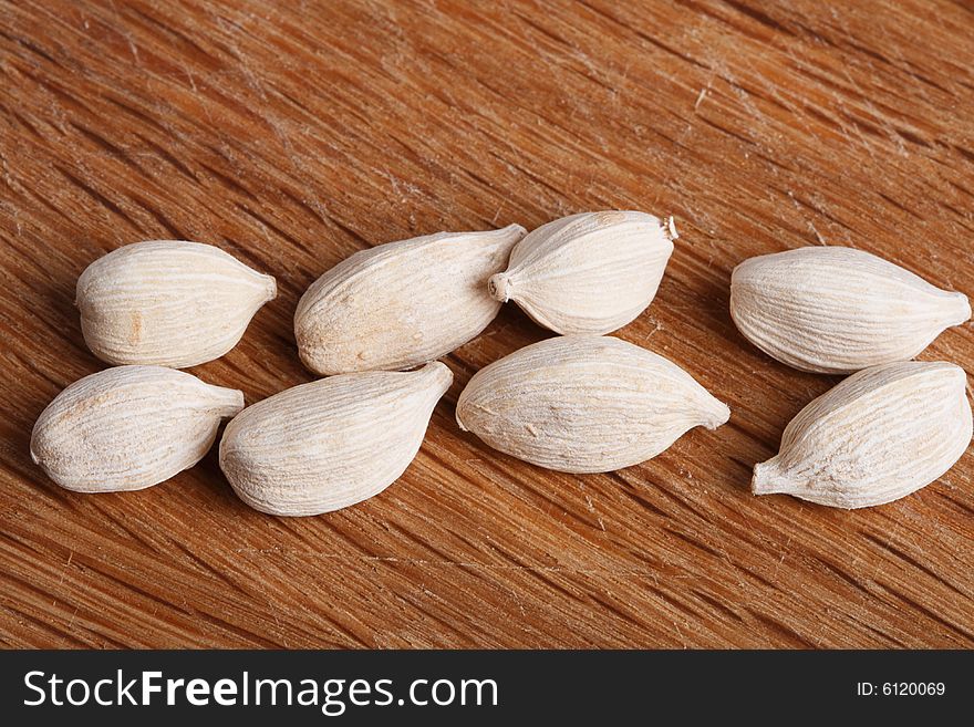 Eight white cardamom pods on old wood, macro