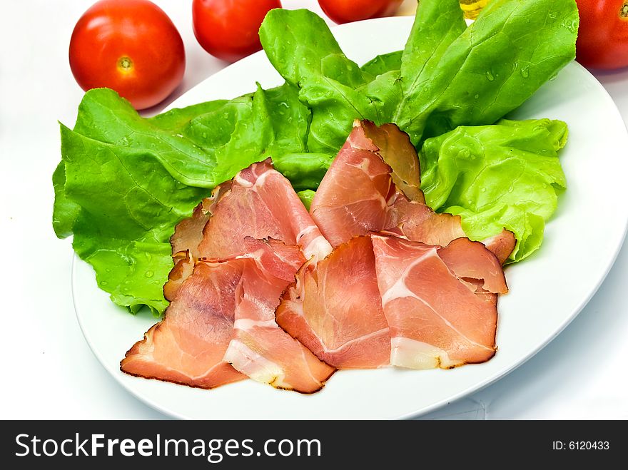 Many smoked slices of ham with salad.