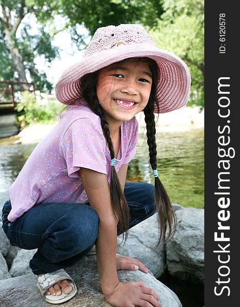 Little girl playing on rocks by river