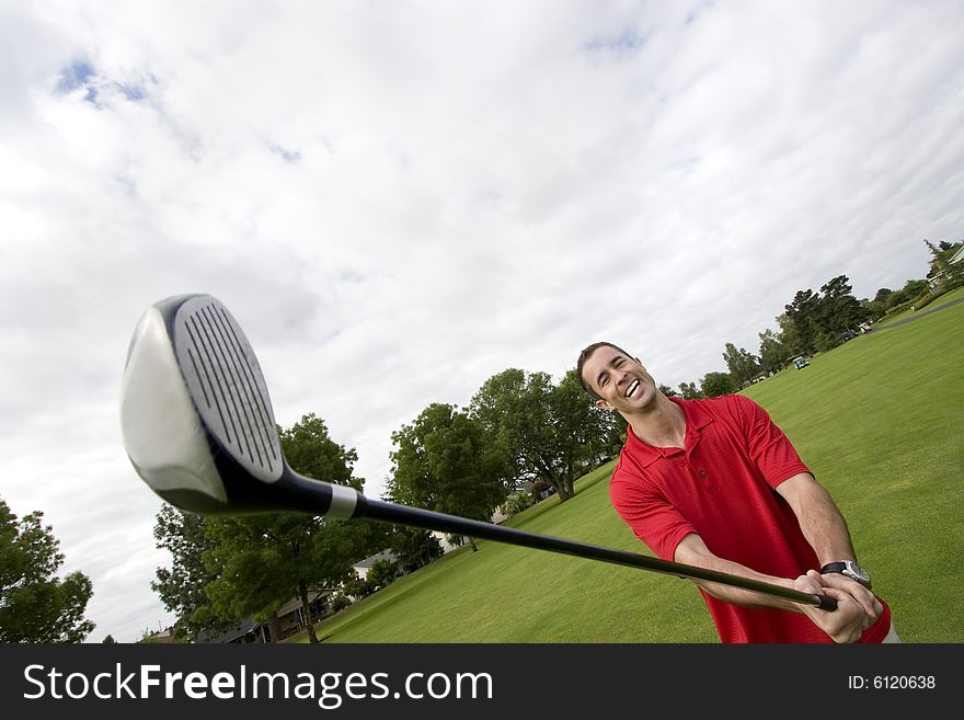 Man holding golf club away from him while he laughs. Horizontally framed photo. Man holding golf club away from him while he laughs. Horizontally framed photo.