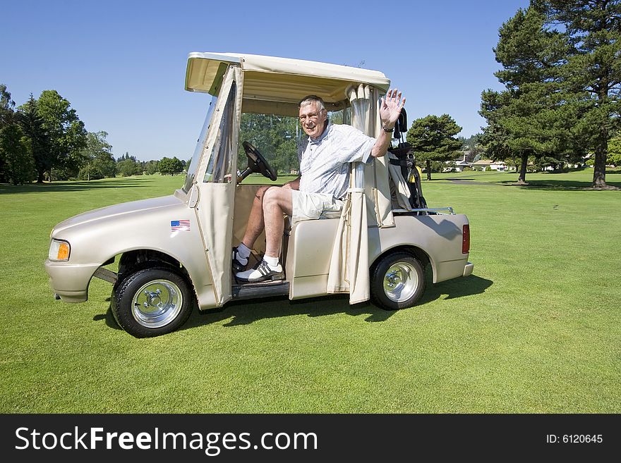 Elderly man smiling and waving while riding in a golf cart. Horizontally framed photo. Elderly man smiling and waving while riding in a golf cart. Horizontally framed photo.