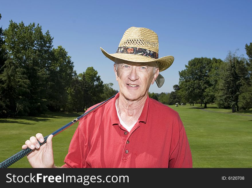 Elderly man holding a golf club and smiling. Horizontally framed photo. Elderly man holding a golf club and smiling. Horizontally framed photo.