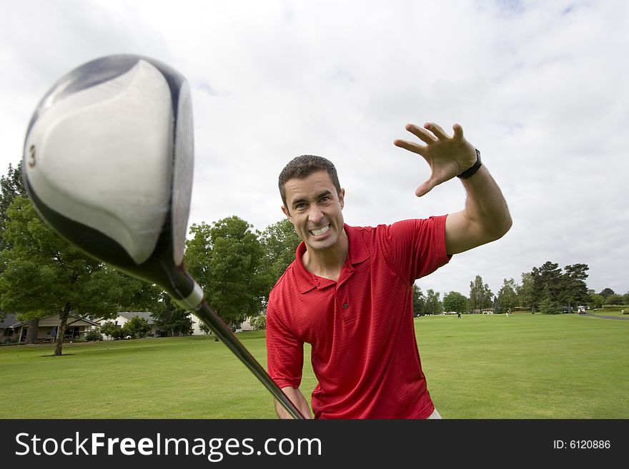 Man holding golf club away from him while he pretends to attack it. Horizontally framed photo. Man holding golf club away from him while he pretends to attack it. Horizontally framed photo.