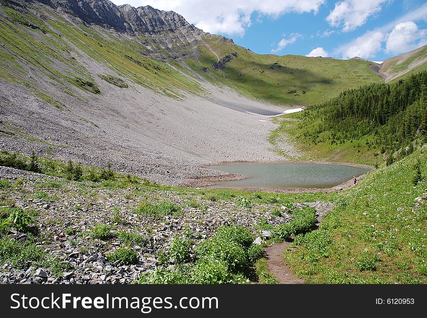Alpine lake and meadows on mountains indefatigable, kananaskis country, alberta, canada
