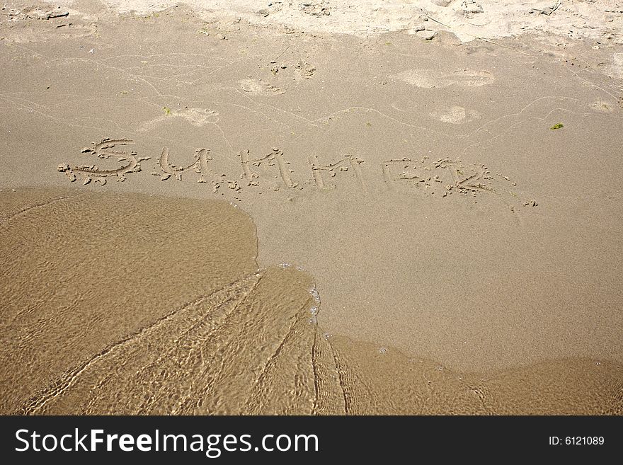 The word summer written in the sand with an approching wave. The word summer written in the sand with an approching wave