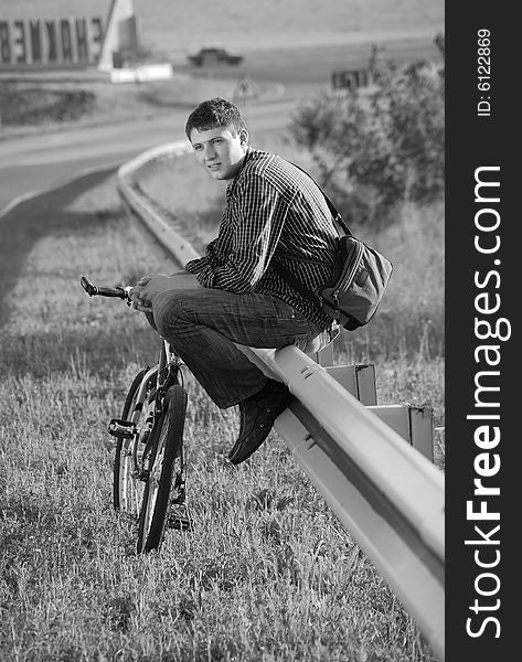 A young man with a bicycle on the highway. A young man with a bicycle on the highway