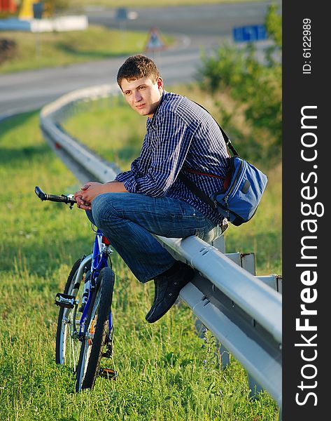 A young man with a bicycle on the highway. A young man with a bicycle on the highway