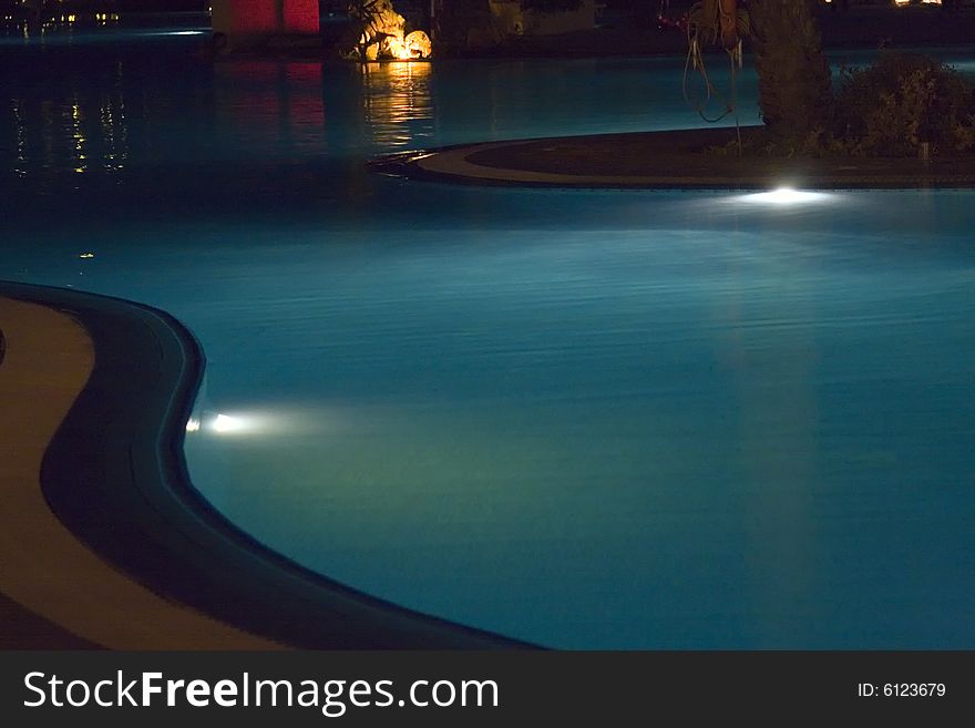 Pool at the hotel resort illuminated by the night lights. Pool at the hotel resort illuminated by the night lights.