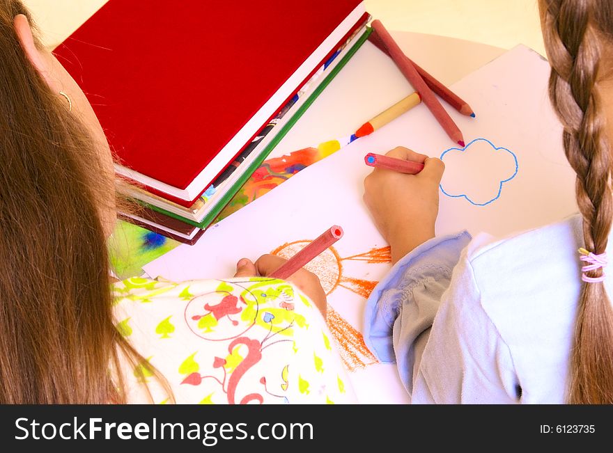 Two girls are drawing by color pencils