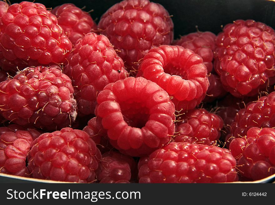 Ripe appetizing raspberries on a black background