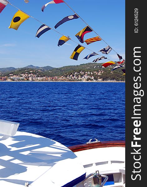 Coloured seafaring flags on a boat. These flags and their meaning costitutes the international code to communicate on sea. View of the city of Alassio in Liguria, Italy. Coloured seafaring flags on a boat. These flags and their meaning costitutes the international code to communicate on sea. View of the city of Alassio in Liguria, Italy.