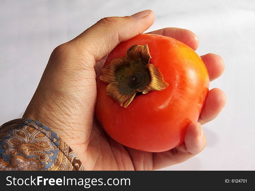 A ripe persimmon in a man's hand. A ripe persimmon in a man's hand