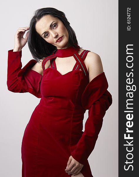 Portrait of a beautiful mature brunette woman with dramatic make-up, wearing a red evening dress. Portrait of a beautiful mature brunette woman with dramatic make-up, wearing a red evening dress