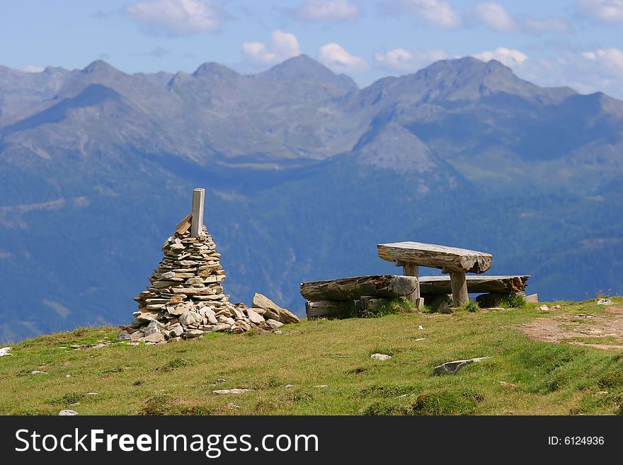 Alpine scenery with stone pile, bench and mountain range