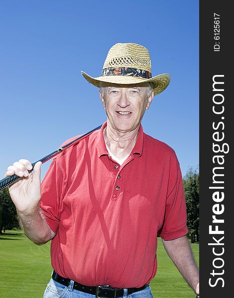 Elderly man holding a golf club and smiling. Vertically framed photo. Elderly man holding a golf club and smiling. Vertically framed photo..