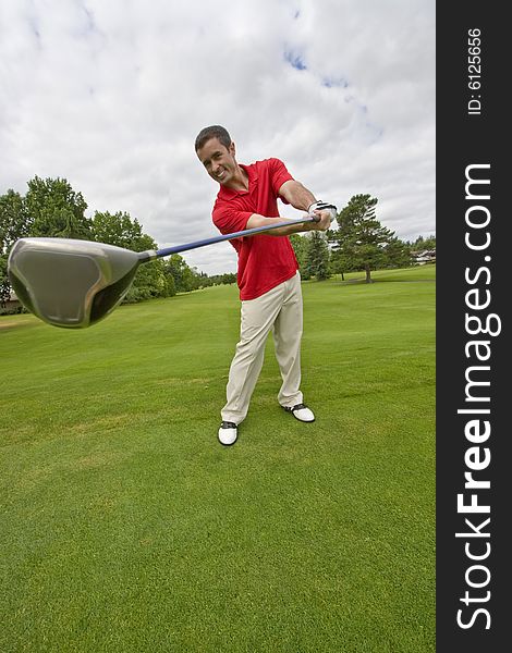 Man holding golf club far away from him and smiling. Vertically framed photo. Man holding golf club far away from him and smiling. Vertically framed photo.