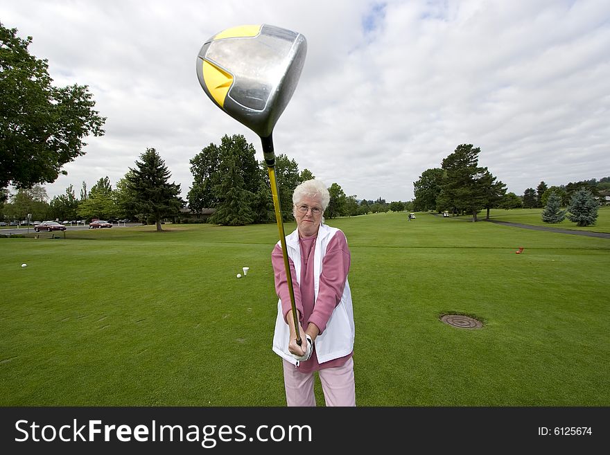 Elderly golfer holding her golf club out. Horizontally framed photo.