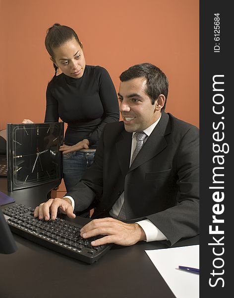 Office woman shows a businessman a giant clock while he types on his computer. Vertically framed photo. Office woman shows a businessman a giant clock while he types on his computer. Vertically framed photo.