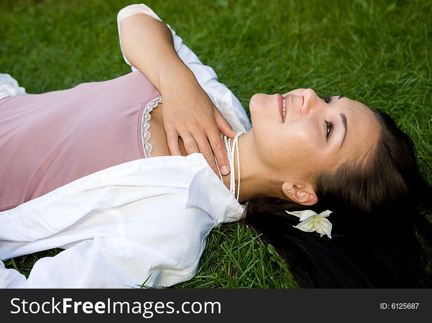 Attractive brunette woman lying on grass. Attractive brunette woman lying on grass