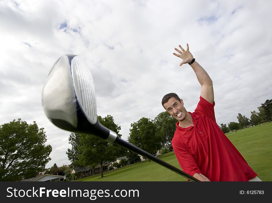 Man holding golf club away from him while he pretends to attack it. Horizontally framed photo. Man holding golf club away from him while he pretends to attack it. Horizontally framed photo.