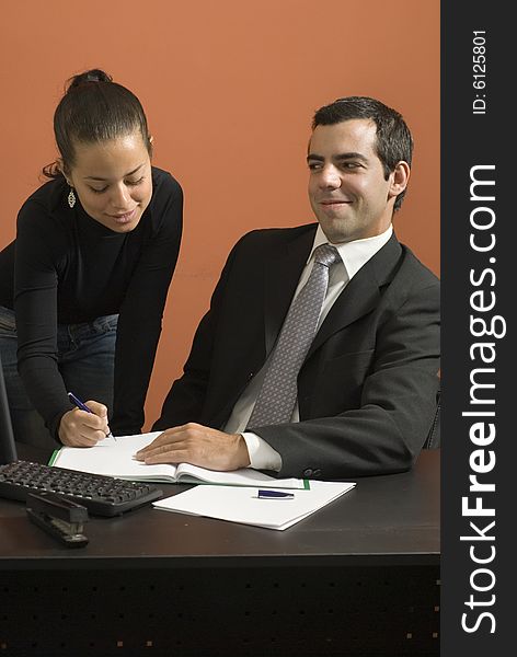 Office woman showing a businessman paperwork as he looks at her. Vertically framed photo. Office woman showing a businessman paperwork as he looks at her. Vertically framed photo.