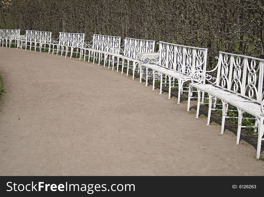 Seven white benches in park