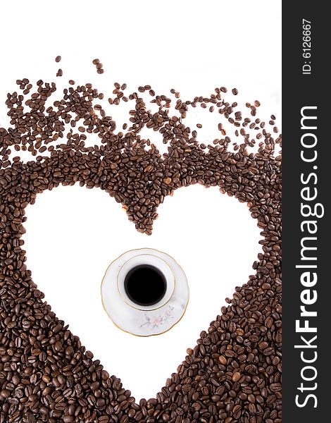 White coffee cup in center of the heart symbol made of coffee beans. White coffee cup in center of the heart symbol made of coffee beans