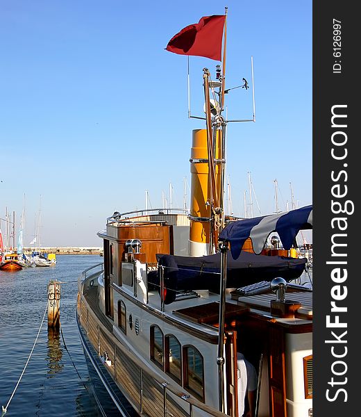 Luxury steam ship with yellow chimney moored in harbour.