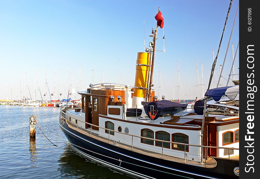 New steam ship with yellow chimney moored in harbour.