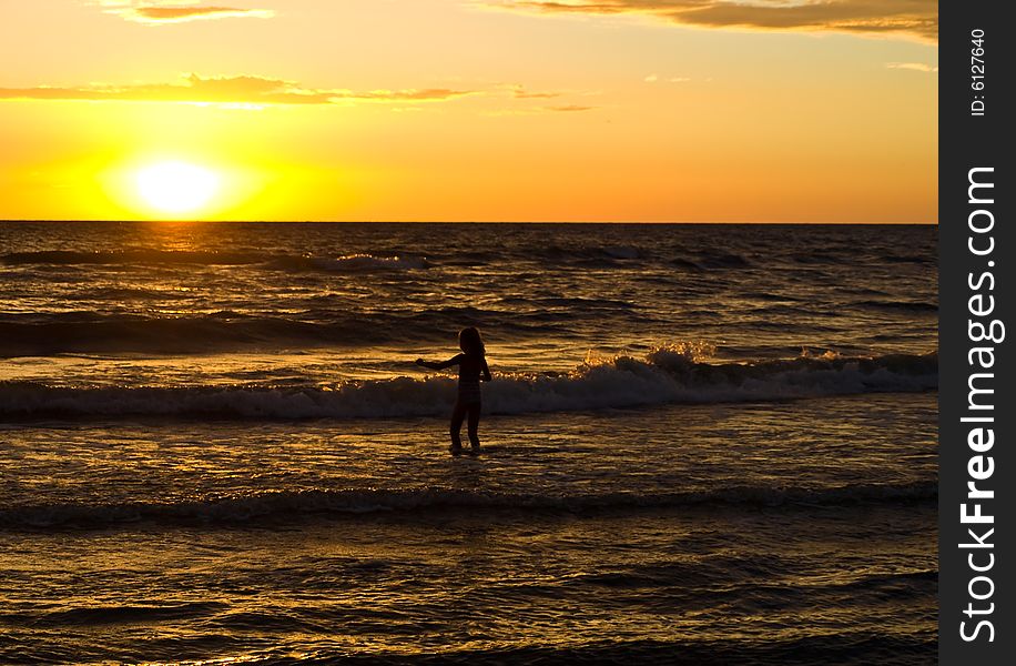 Child in the sea while sun falling. Child in the sea while sun falling