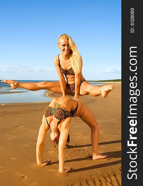 Two acrobatic girl on the beach doing acrobatic excersises