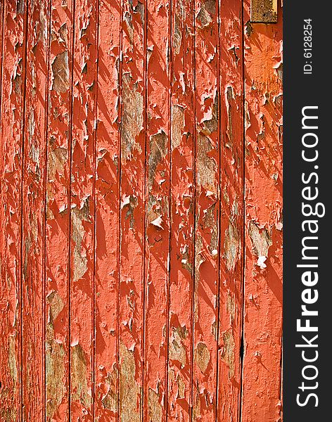 The texture and pattern of peeling red paint on a door. The texture and pattern of peeling red paint on a door
