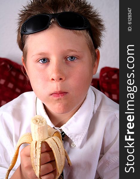 Sweet young boy is eating a banana