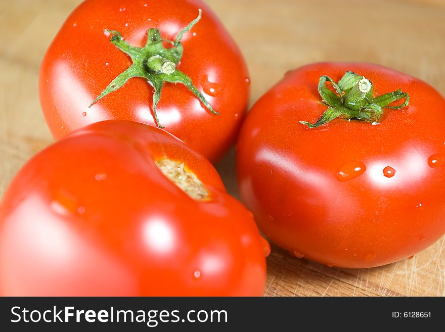 Three fresh tomatoes on wooden desk