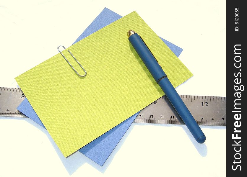 Pen, colored papers, and ruler against white background. Pen, colored papers, and ruler against white background