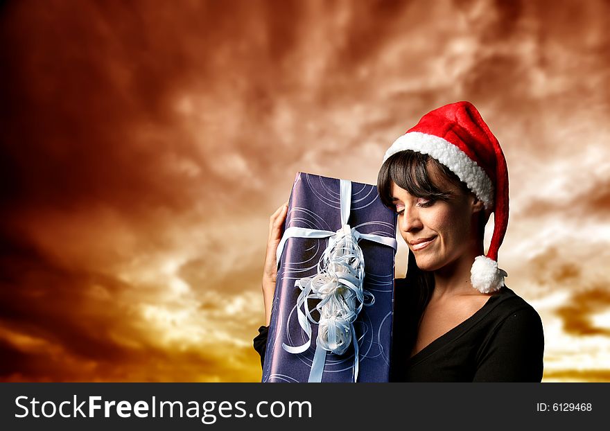 Young woman wearing santa claus hat with a present. Young woman wearing santa claus hat with a present