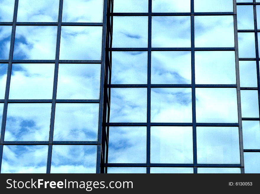 A building that has an interesting set of windows, with clouds reflected in the glass. A building that has an interesting set of windows, with clouds reflected in the glass.