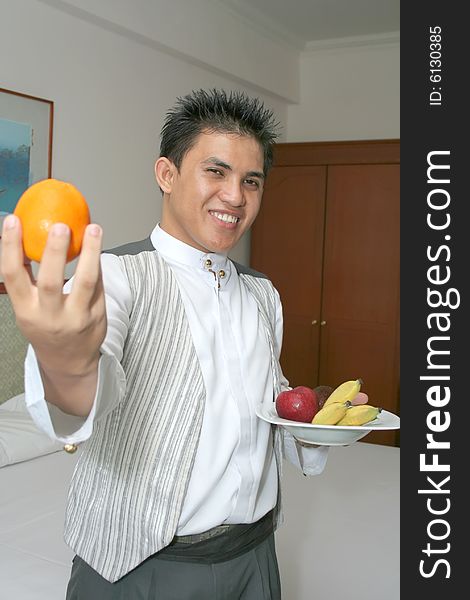 Room service waiter deliver fruit in hotel room smiling