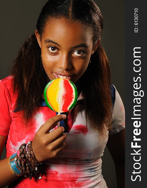 Portrait of young african girl eating a lollipop with happy expression. Portrait of young african girl eating a lollipop with happy expression