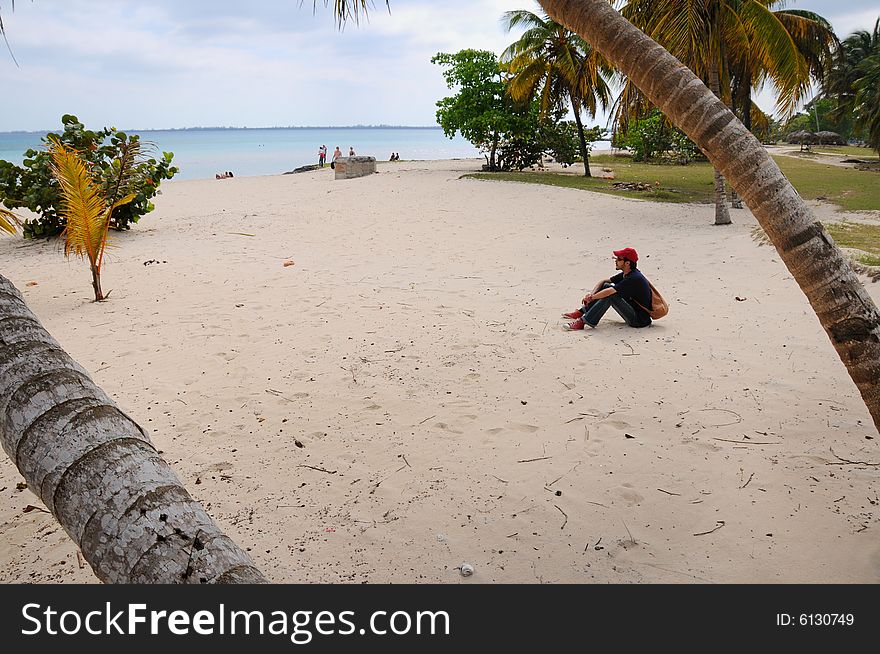 Portrait of young man sitting on the sand - relaxing on the beach