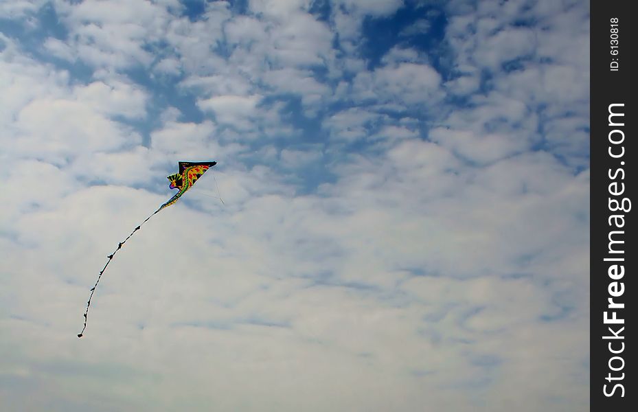 A colorful kite flying high in a blue sky of puffy white clouds. A colorful kite flying high in a blue sky of puffy white clouds